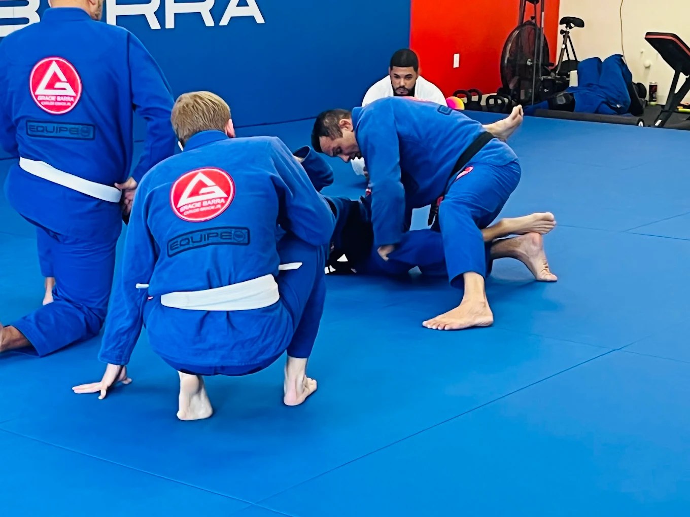 Students in blue gis training Brazilian Jiu-Jitsu on the mats at Gracie Barra Seminole in Longwood, FL.